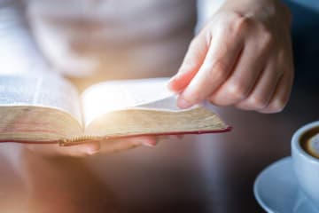 A hand turning a page in a Bible