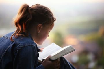 woman reading her bible outside