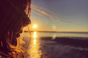 Woman standing in front of an ocean sunset