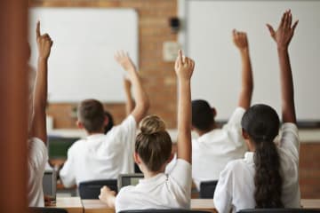 students in uniforms raising hands