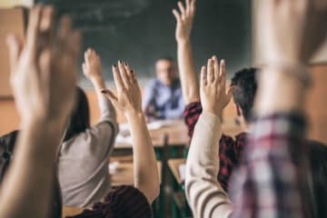 students raising their hand in the classroom