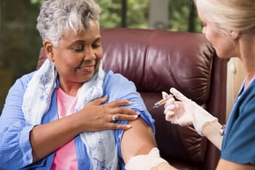 nurse vaccinating an older woman