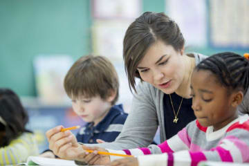 Teacher helps a young student with writing assignment