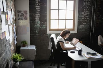 Woman sitting at desk in office next to window