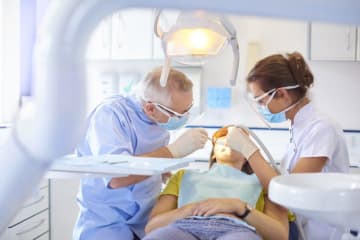 Dentist and hygienist work on a patient's teeth