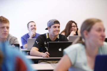 College students smile while facing ahead towards the professor