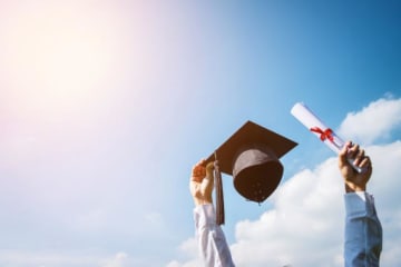 Man holding cap and diploma up in the sky