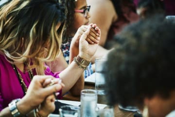 people holding hands at a table