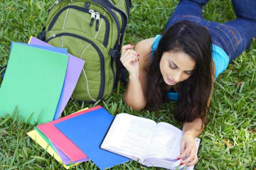 A student reading her notes outside in the grass