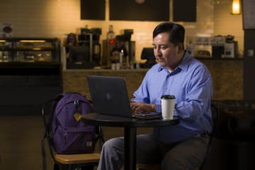 man working on a computer in a coffee shop