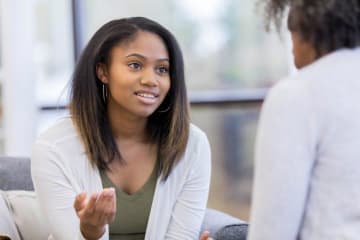 Young African-American female has hope in eyes talking with a psychologist