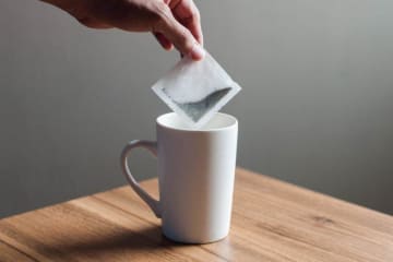 A tea bag being dipped into a cup