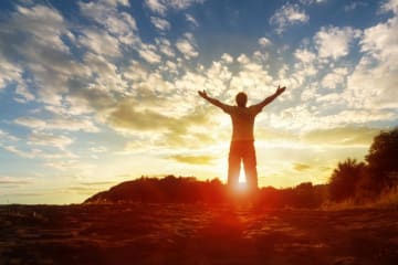 A man with his arms spread towards the sunset