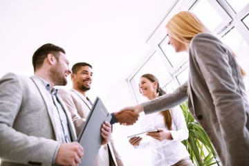 4 professionals greet each other before a business meeting