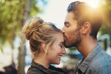 A man kissing a woman on her forehead