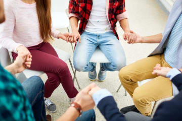 people sitting in a circle and holding hands