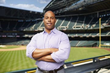 man in a dress shirt standing in front of a stadium