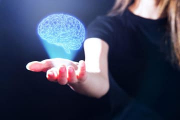 Woman holds her hand out with a virtual brain above it 