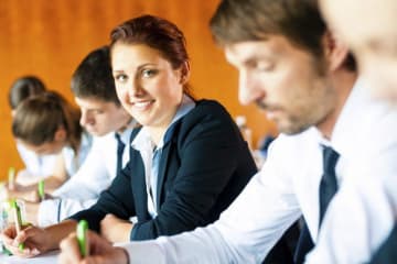 Group of professionals take assessment and girl turns head to smile