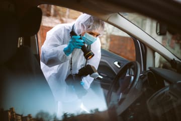 Forensic photographer taking crime scene photos of physical evidence in car