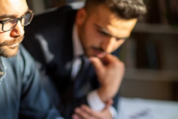 Two male market research analysts reviewing reports