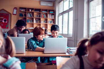 Students using laptop computers in classroom to complete work online