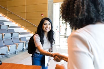 female student and teacher shaking hands when talking during office hours