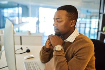 man praying at desk for God's help in walking humbly