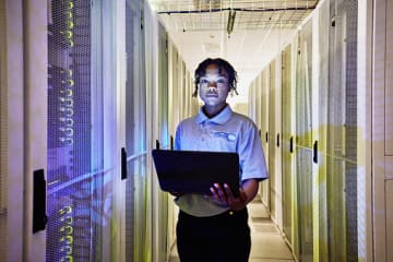 Female computer engineer programs computers in a server room