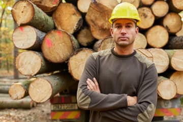 professional forester in front of logs