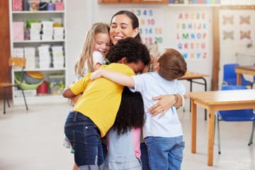 Diverse learners hugging their teacher