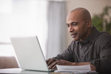 Professor replying to emails on laptop