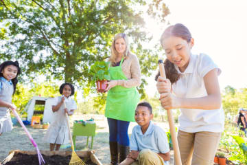 Teacher and elementary students planting a garden outside