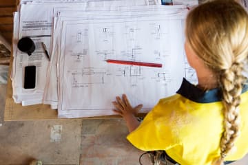 Female project engineering student reviewing blueprints at desk