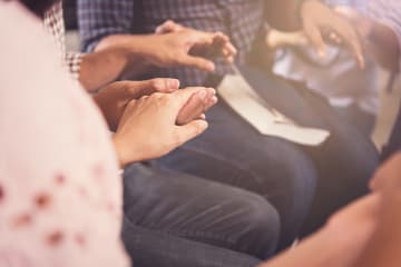 Christians encouraging one another by holding hands and praying