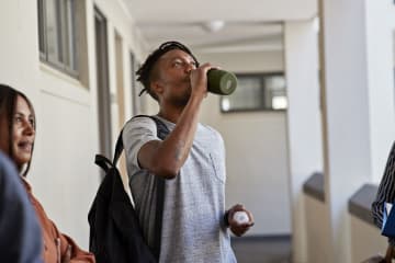 African-American male student drinking water