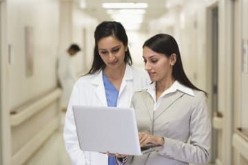 Hospital administrator showing something to a doctor on the computer