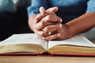 Hands praying over Bible