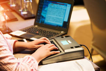 A stenographer working at a computer