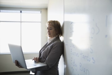 Spanish teacher working on laptop in front of whiteboard