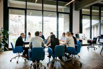 Business meeting in a large board room with tall windows