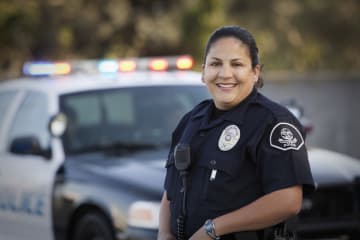 Woman police officer standing beside police vehicle