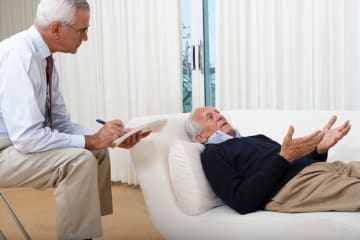 Psychologist psychoanalyzes patient on white couch near window