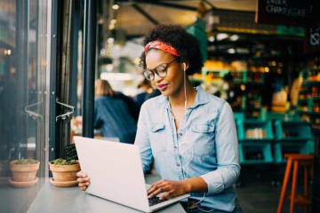 Woman studying at a coffee shop with a laptop and glasses