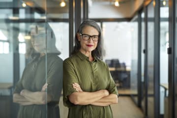 Smiling entrepreneur leaning against a glass wall