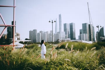 Woman standing in grass field looking at the city