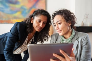 Diversity and inclusion specialist discussing information on tablet with coworker