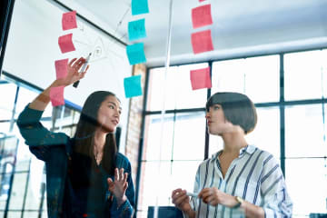 Two coworkers organizing sticky notes in midair