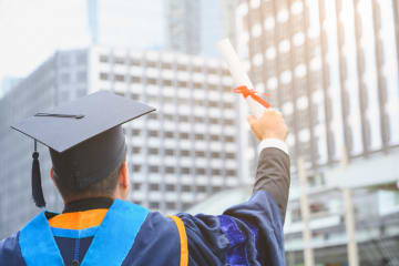 A PhD student holding up his diploma 