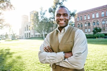 male EdS professor smiling outside of school building